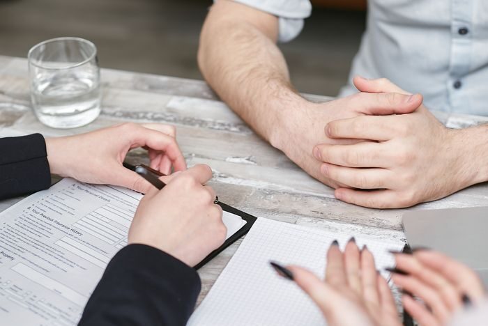 Close-up view of a team meeting with documents and notebooks on a wooden desk.